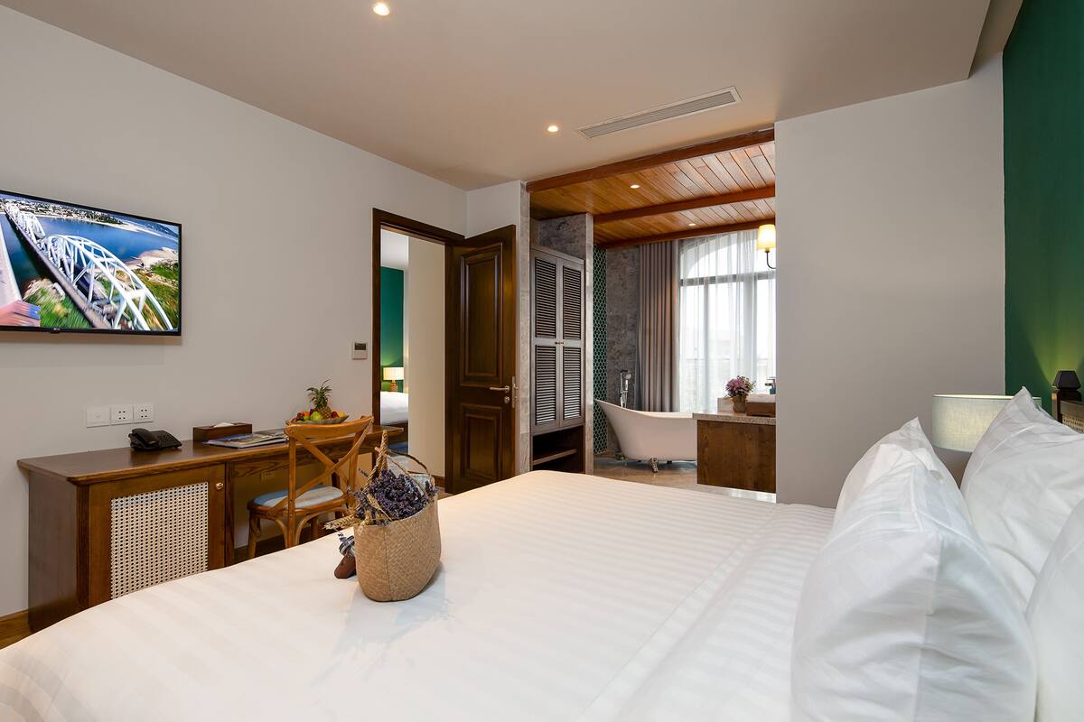 Een hotelkamer met een bed, een bureau, een stoel, een televisie, een badkamer en een raam.