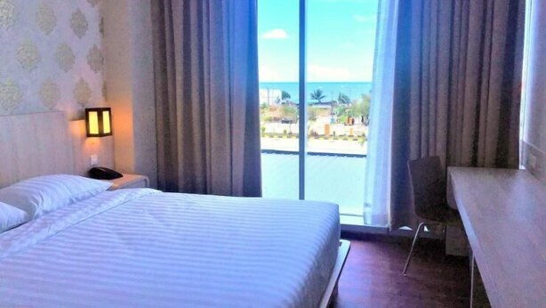 Une chambre d’hôtel avec un lit, un bureau et une vue sur la mer.