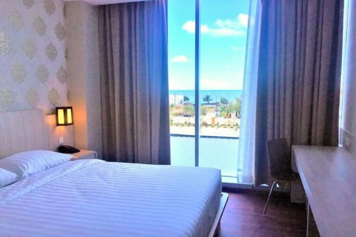 Una habitación de hotel con cama, escritorio y vista al mar.