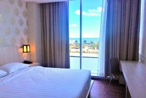 A hotel room with a bed, a desk, and a view of the sea. - Ancyra Hotel (Poso)