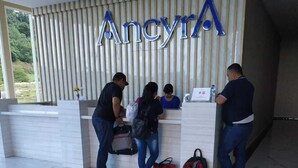 Un comptoir d’accueil avec une enseigne portant le nom « Ancyra », situé dans un bâtiment moderne au revêtement de sol en marbre.