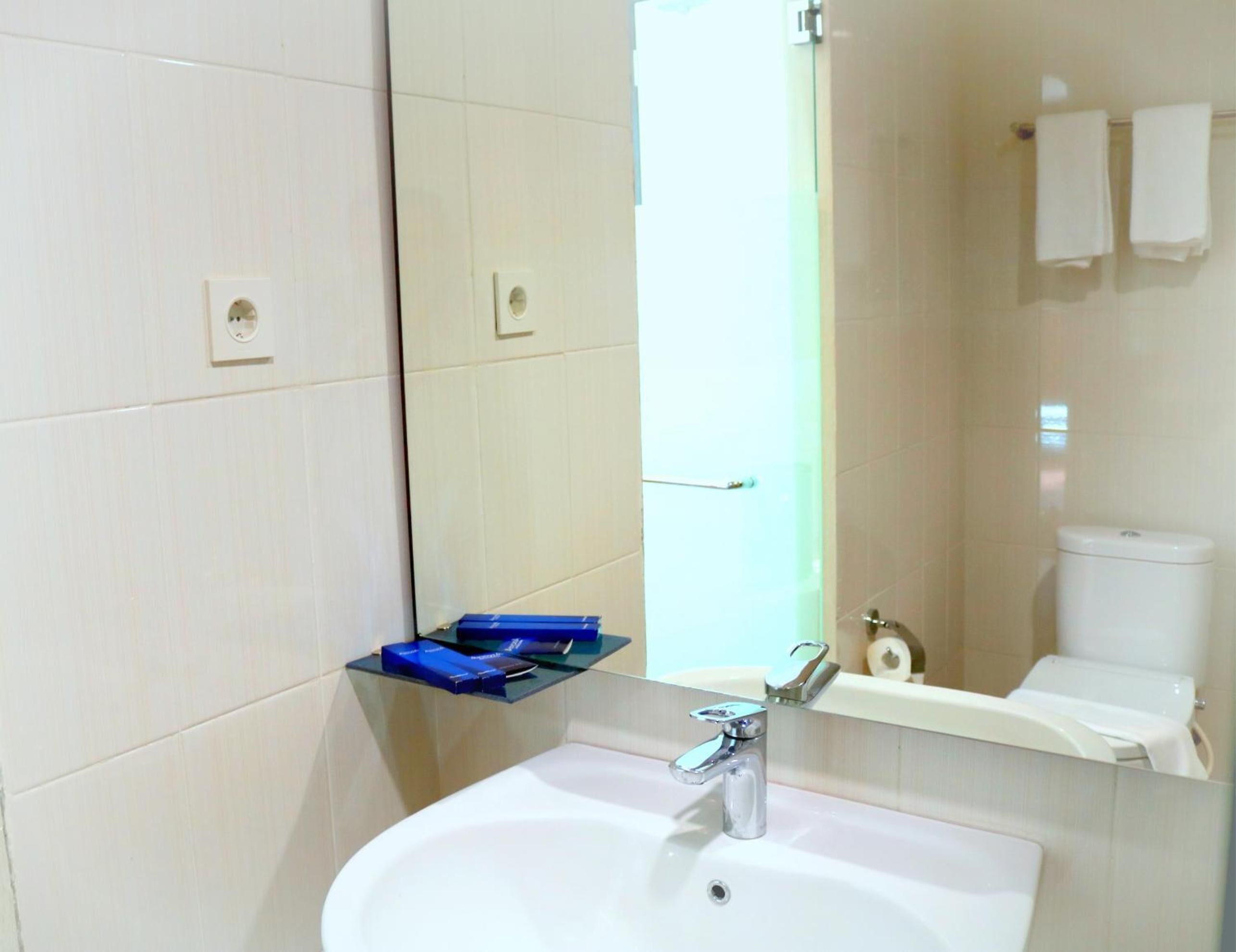 A bathroom with a white sink, a mirror, a toilet, and a towel rack.