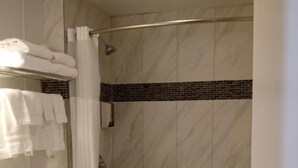 A bathroom with a toilet, sink, and shower area. - Modoc Inn (Alturas)