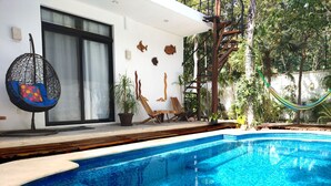 A swimming pool with a tiled edge, a hanging chair, and a hammock.