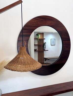 Een ronde spiegel met houten lijst aan de muur.