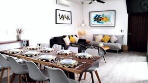 A dining area with a wooden table set for six, surrounded by grey chairs.