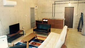 A compact living space with a flat-screen TV, a sofa, a small wooden table, and a bench. - Retya (Ishigaki)