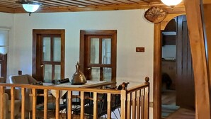 A dining area with a wooden table and chairs, two doors, and a ceiling with wooden beams and hanging lights.