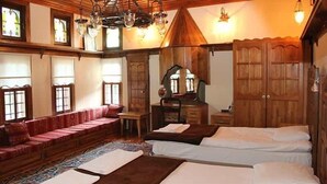 A traditional room with a wooden ceiling, a sofa, a bed, and a desk.
