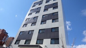A modern multi-story building with a symmetrical facade, large windows, and a flat roof. - Lic Plaza Hotel (Long Island City)