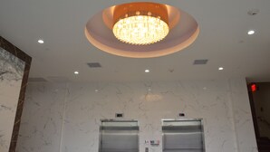 A lobby with a marble wall, a chandelier, two elevators, and a "No Smoking" sign. - Lic Plaza Hotel (Long Island City)
