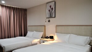 A hotel room with two beds, a nightstand with a phone, and a wall-mounted lamp. - Lic Plaza Hotel (Long Island City)