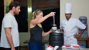 A chef preparing food with a large pot and a strainer, a person observing, and another person in a chef's uniform. - Blue Magpie Lodge (Kalawana)