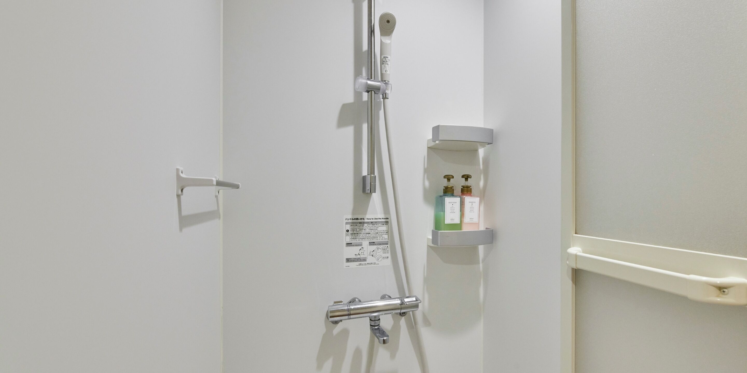 Un baño con ducha, toallero y dispensador de jabón.