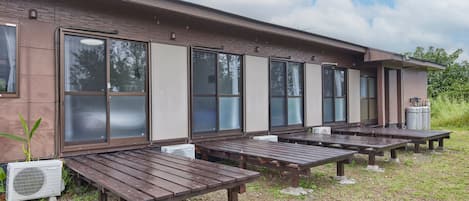 A building with large windows, outdoor wooden benches, and an air conditioning unit.