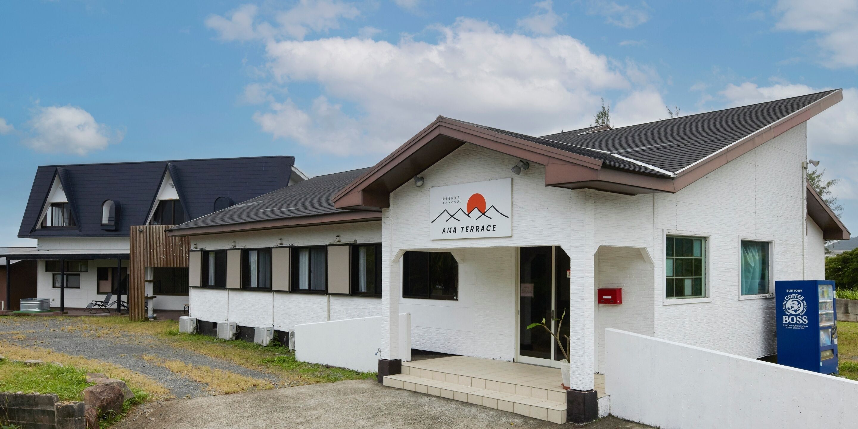A building with a sign reading "AMA TERRACE" and a Suntory Coffee Boss vending machine.