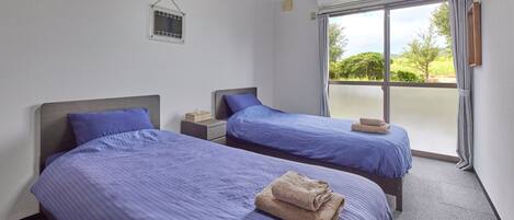 Habitación de hotel con dos camas, una ventana pequeña y vistas a zonas verdes.
