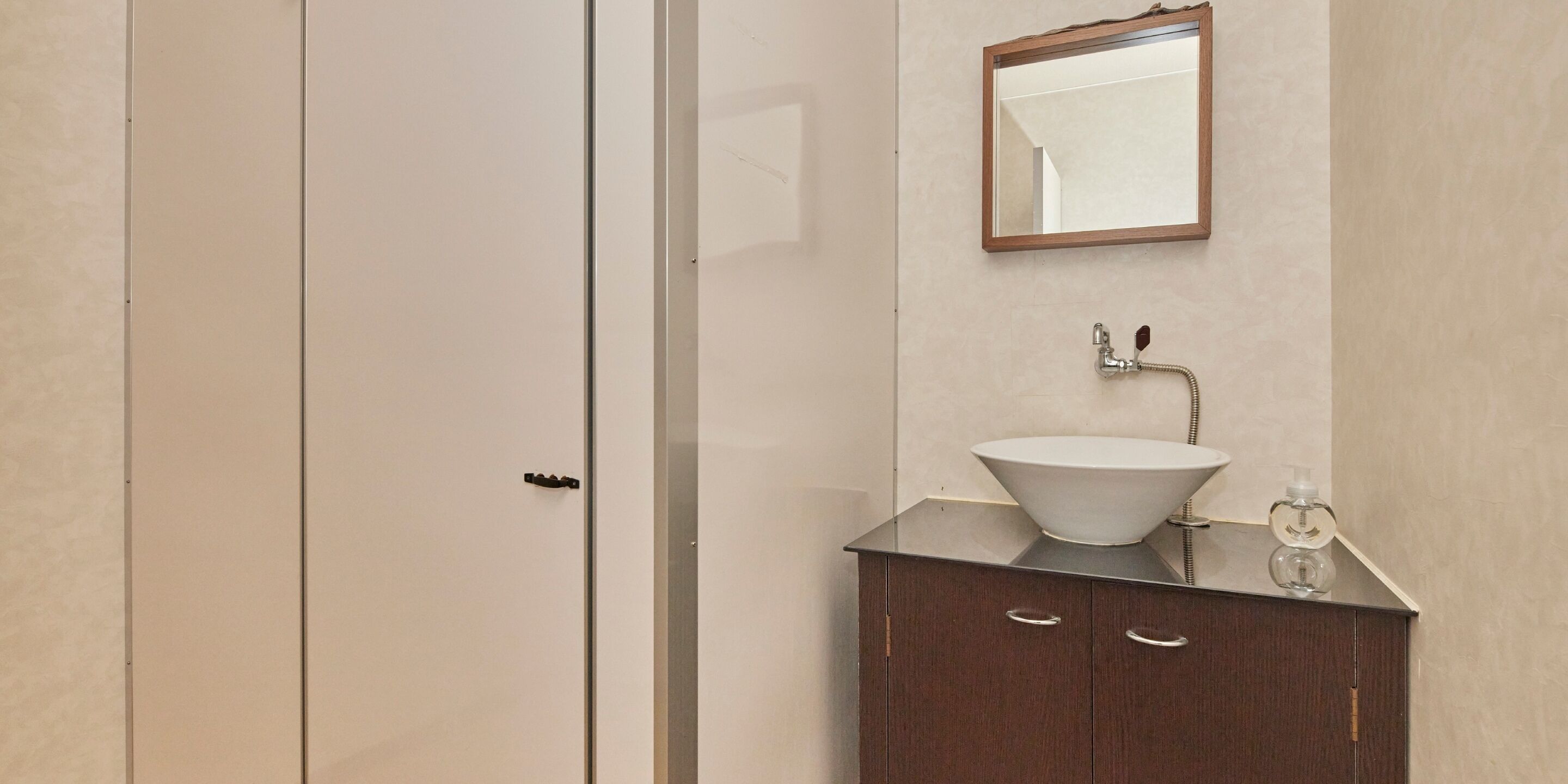 A bathroom with a white sink, a mirror, and a dark wooden cabinet.