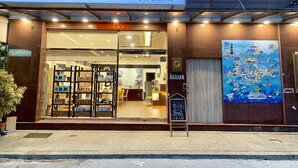 A hotel entrance with a large sign, a glass door, and a poster on the wall. - PHSea Inn (Magong)