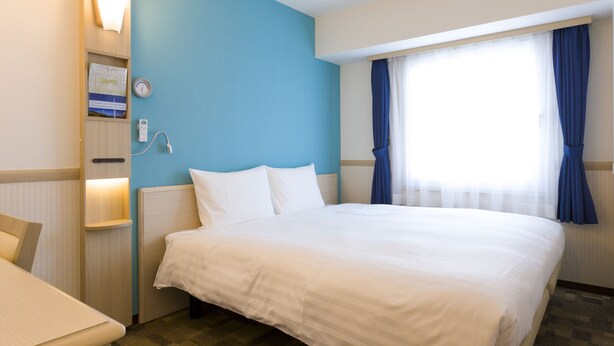 A hotel room with a bed, a desk, a wall-mounted phone, and a window with curtains. - Toyoko Inn Akabane Station Higashi (Tokyo)