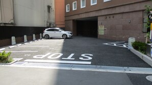 A parking area with a white car parked in a designated space marked with a stop line. - Toyoko Inn Akabane Station Higashi (Tokyo)