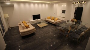 A modern living room with a sofa, a glass coffee table, and a dining table with chairs. - Superior Apartments (Tbilisi)
