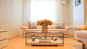 A living room with a glass coffee table, a beige sofa, and a vase of flowers. - Superior Apartments (Tbilisi)