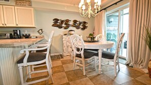 A kitchen with white cabinetry, a dining table with four chairs, a chandelier, and a decorative fish wall art. - Harbour Island 102M 2 Bedroom Condo by RedAwning (Ocean City)