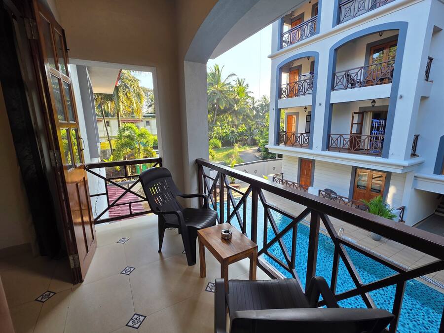 A balcony with a pool, a table, and two chairs.