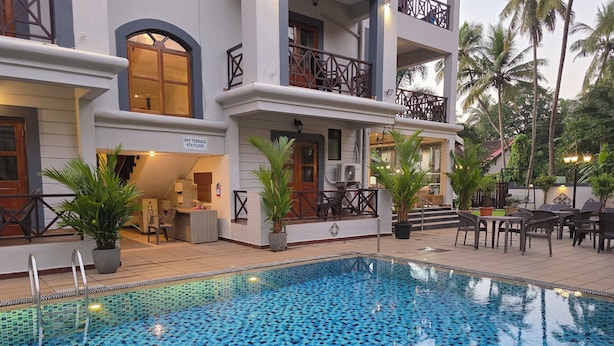 A hotel with a pool area featuring a tiled floor, outdoor seating, and a sign indicating the Sky Terrace on the 4th floor. - Coastal Suites Apart-Hotel (Benaulim)