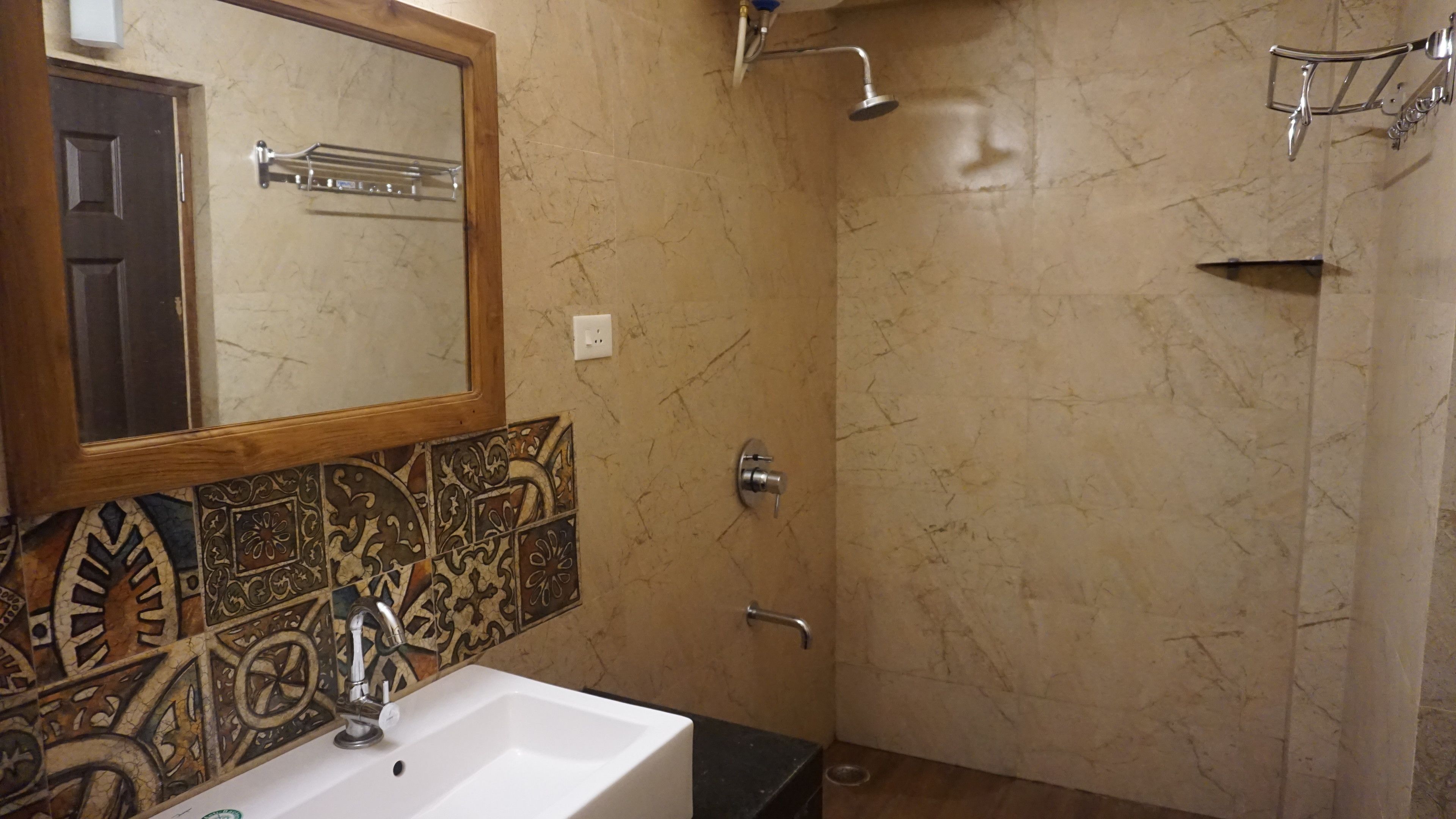 A bathroom with a sink, mirror, shower, and tiled walls.