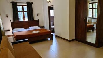 Un dormitorio con cama, sofá, armario y baño a la vista a través de una puerta abierta.