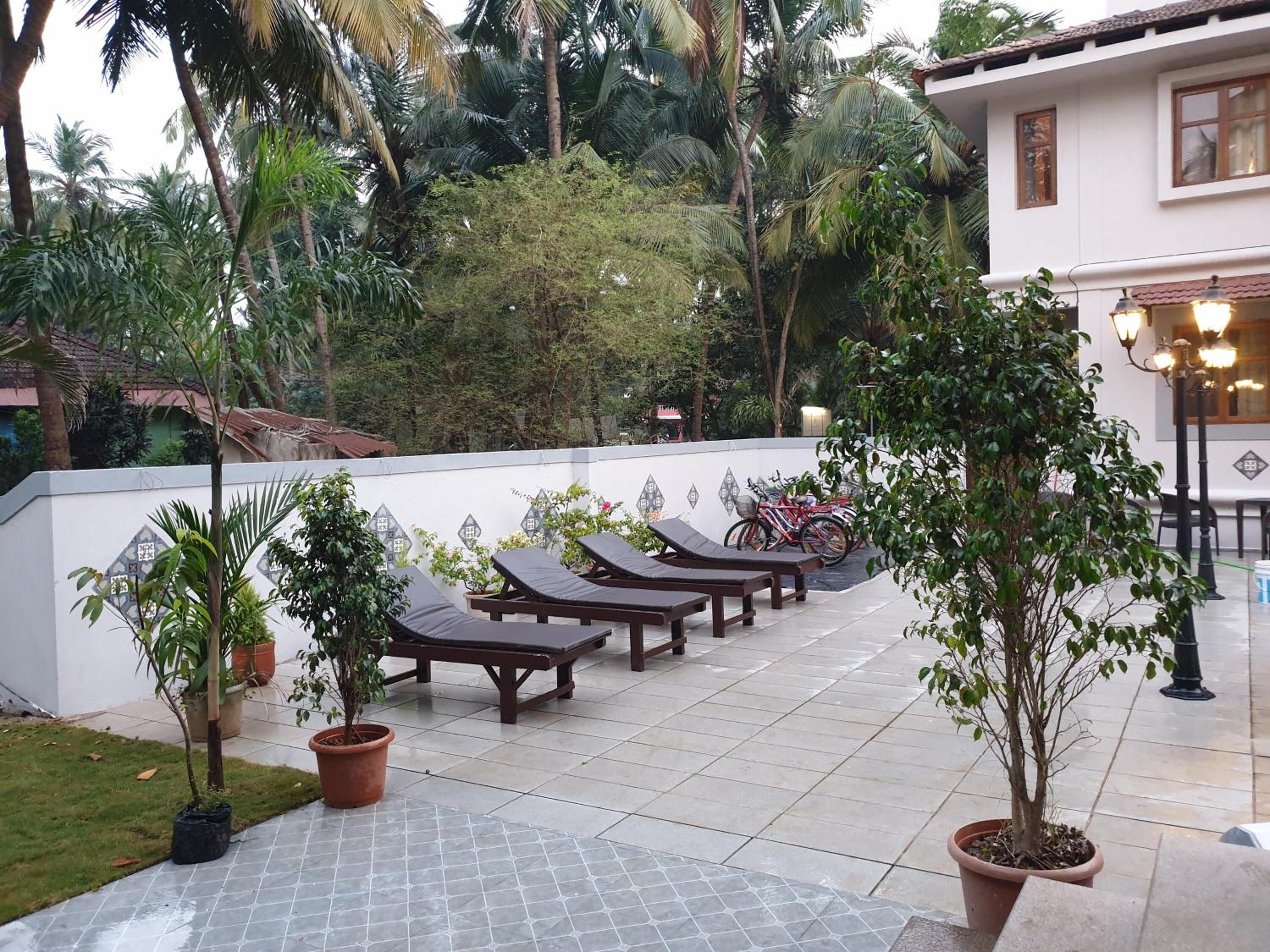 Un patio amueblado con sillones de descanso, plantas en macetas y piso de baldosas.