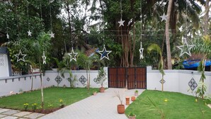 A garden with a paved walkway, potted plants, and decorative stars. - Coastal Suites Apart-Hotel (Benaulim)