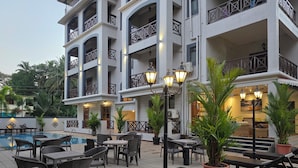 A hotel with outdoor seating, a pool, and multiple balconies. - Coastal Suites Apart-Hotel (Benaulim)
