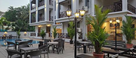 A hotel with outdoor seating, a pool, and multiple balconies.