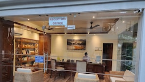 A reception area with wicker furniture, a ceiling fan, and a sign indicating a reception office. - Coastal Suites Apart-Hotel (Benaulim)