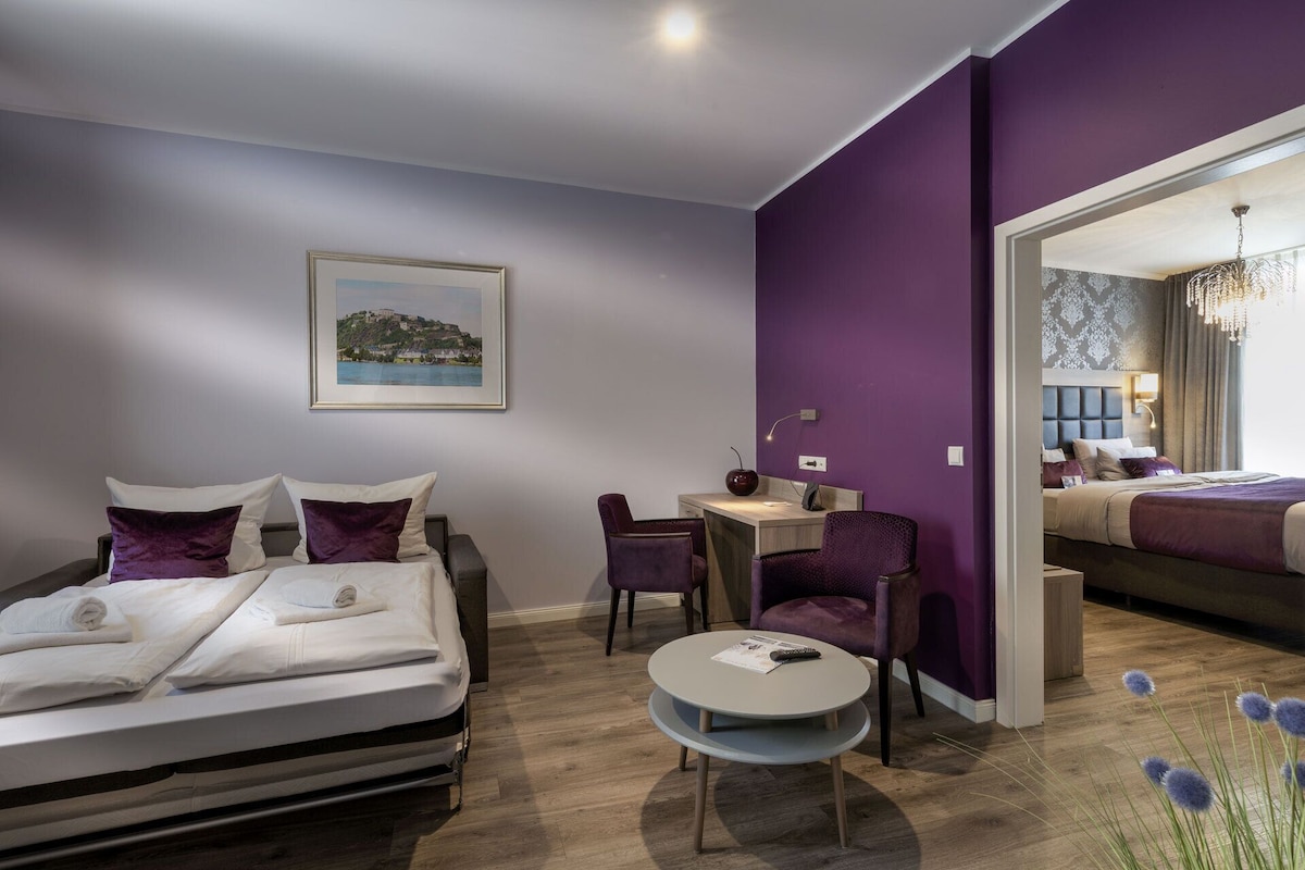 A modern hotel room with a bed, a desk, and a chair.