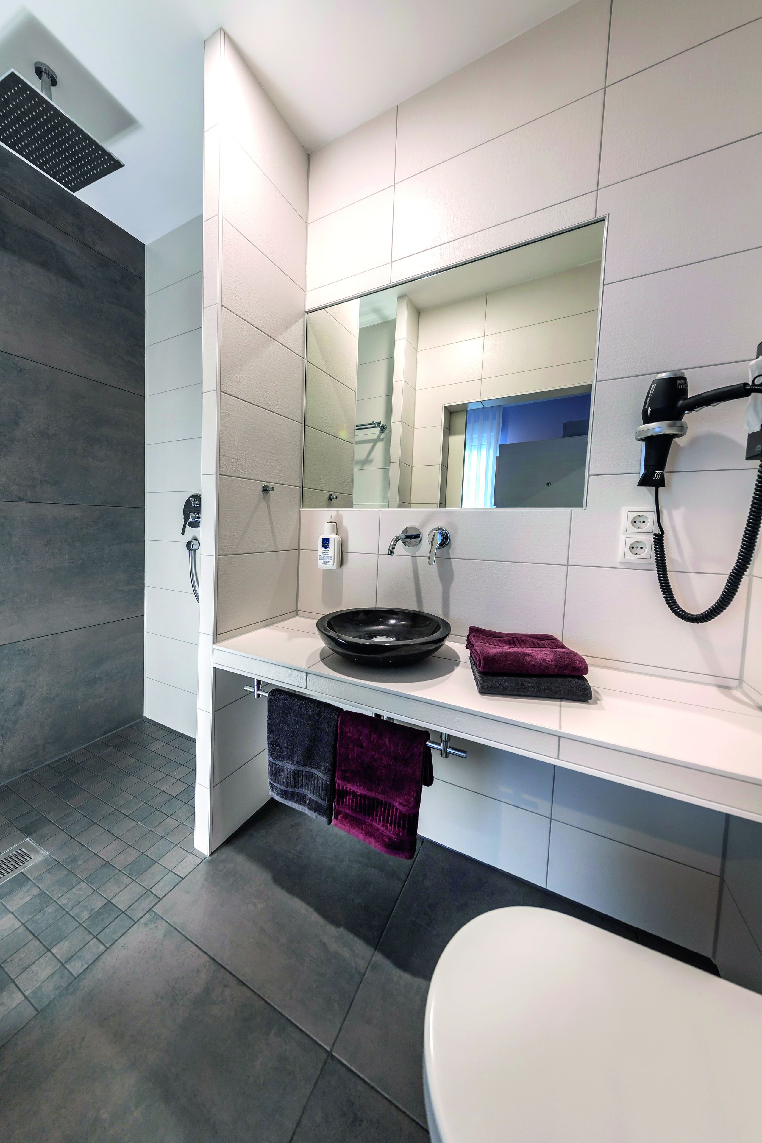 A modern bathroom with a shower, sink, and toilet.