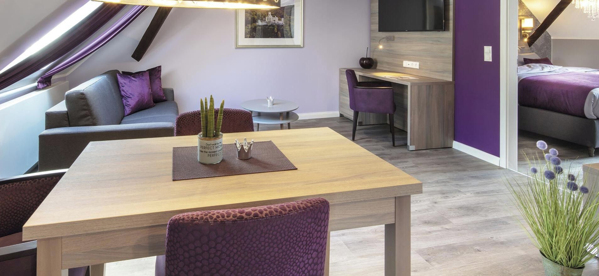 A modern interior with a dining area, a sofa, a desk, and a bed.