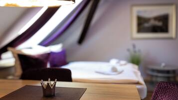A hotel room with a bed, a small table with a decorative item, a chair, and a wall-mounted picture.
