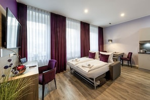 A hotel room with a bed, a desk, a chair, and a TV. - Burgenheimat (Rhens)