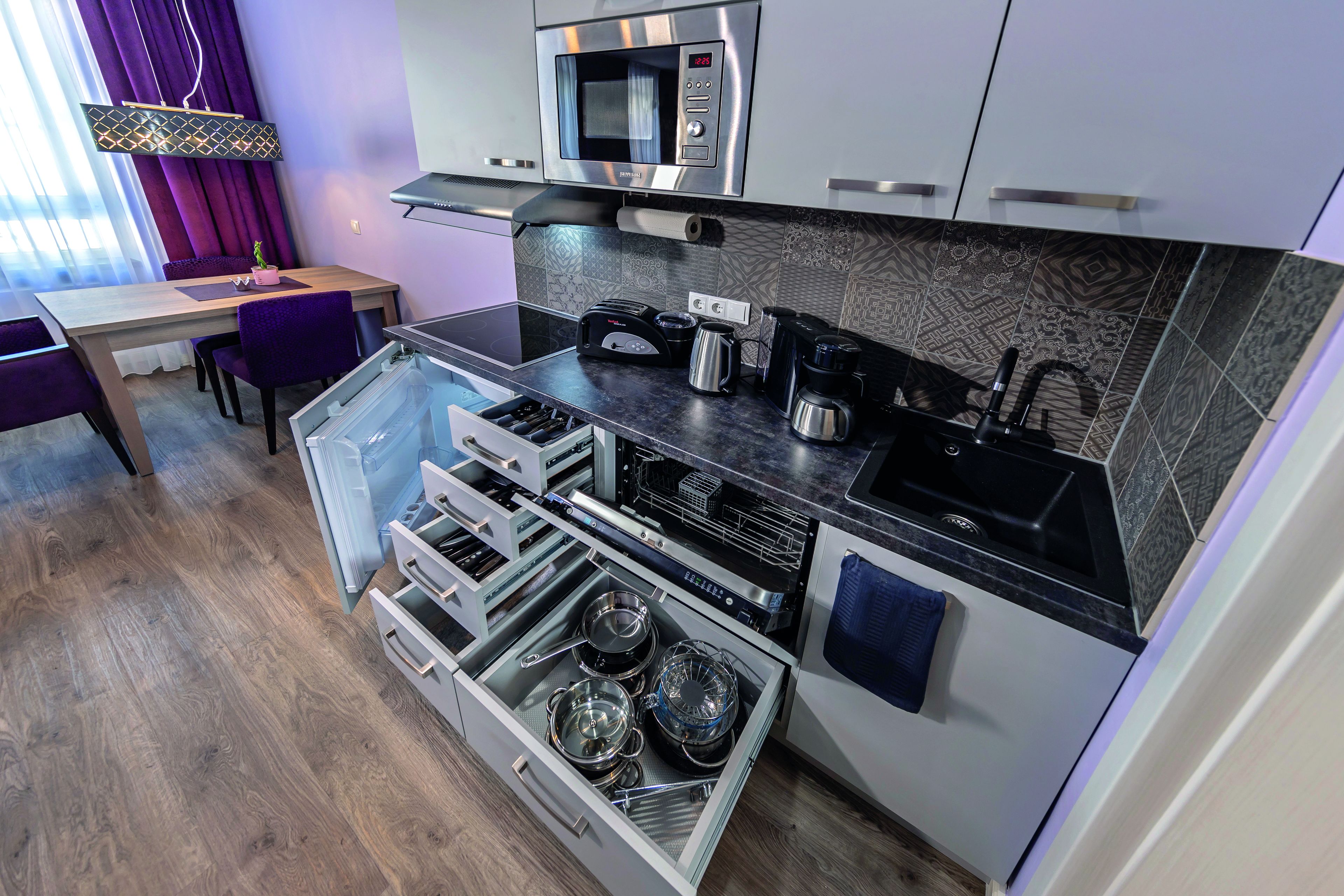 Een moderne keuken met een magnetron, broodrooster, koffiezetapparaat en een inbouwoven.