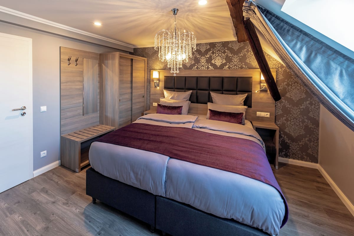 A bedroom with a large bed, built-in wardrobe, and a chandelier.