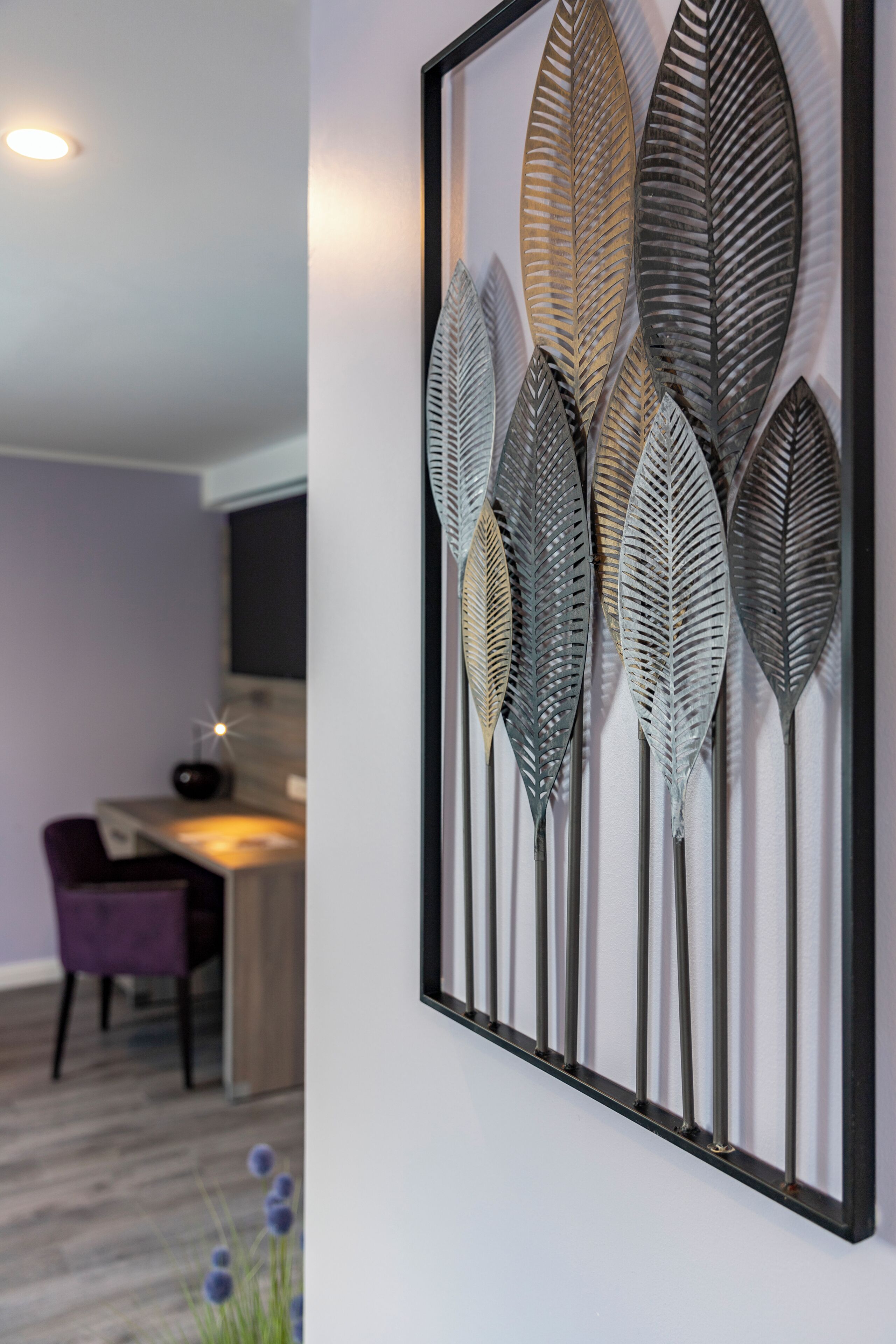 Een lijstwerk met structuren die op bladeren lijken, op een muur.