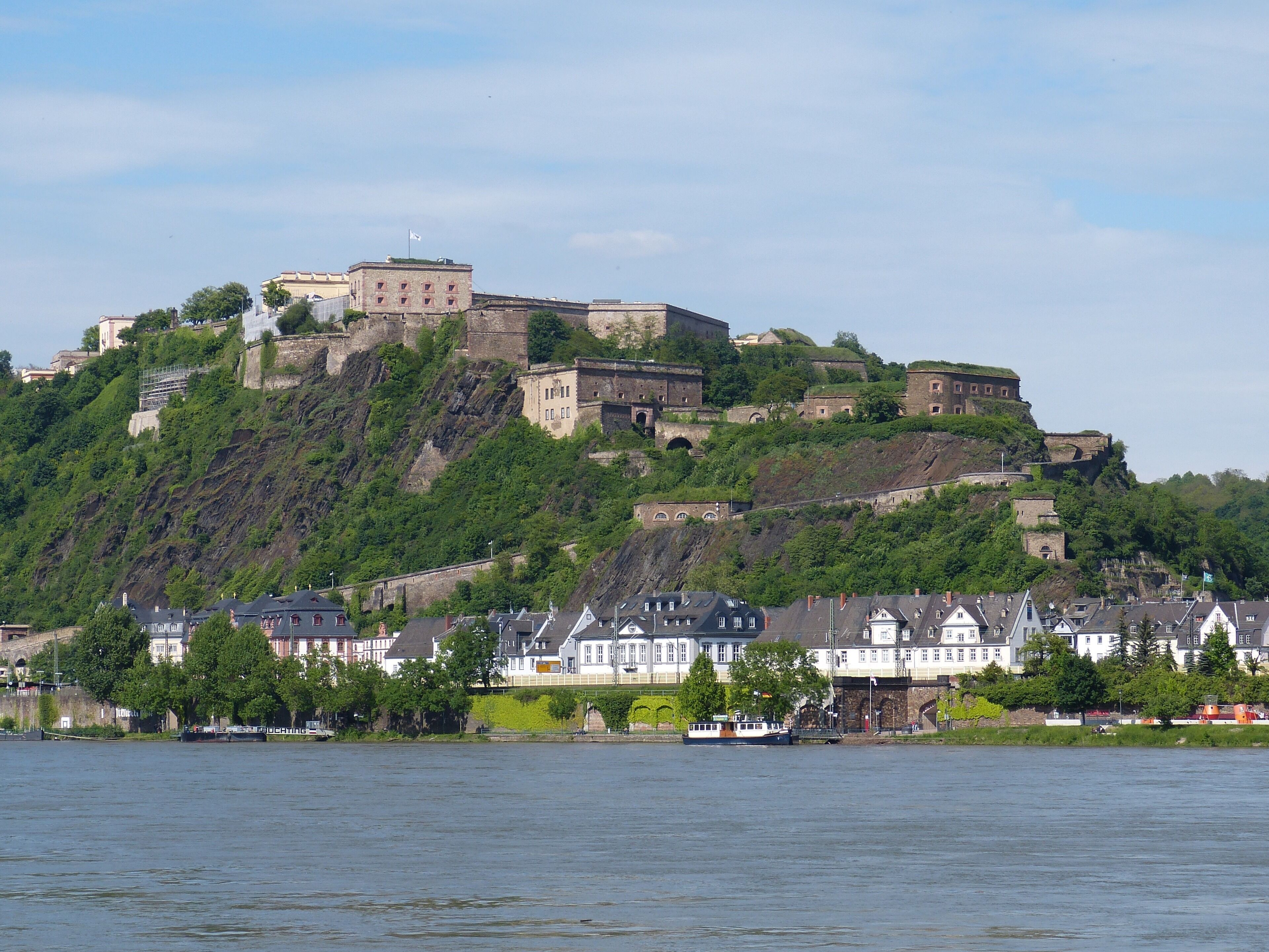 A historic castle on a hill with traditional houses in the foreground.