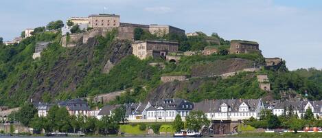A historic castle on a hill with traditional houses in the foreground.