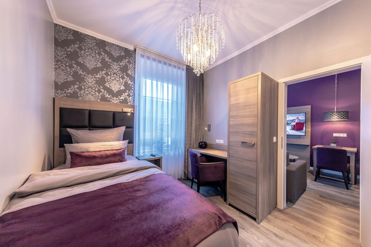 A modern bedroom with a bed, desk, and TV.