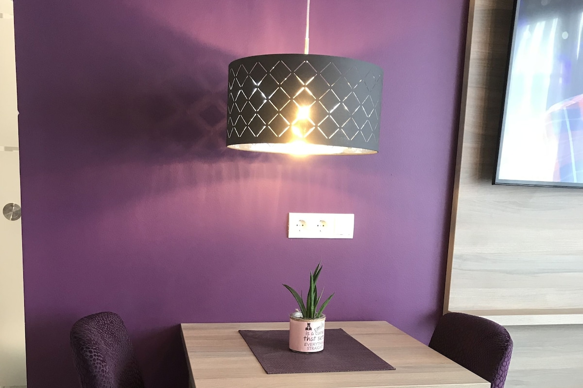 A dining area with a table, chairs, a pendant light, and a potted plant.
