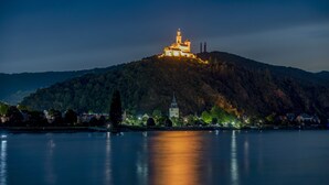 A castle on a hill overlooking a calm lake at night. - Burgenheimat (Rhens)